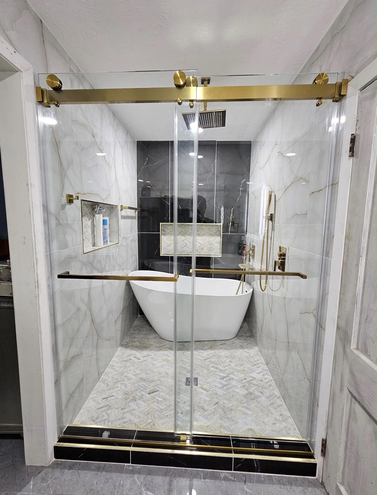 Marble bathroom by LL General Contractor with a freestanding tub and brass fixtures