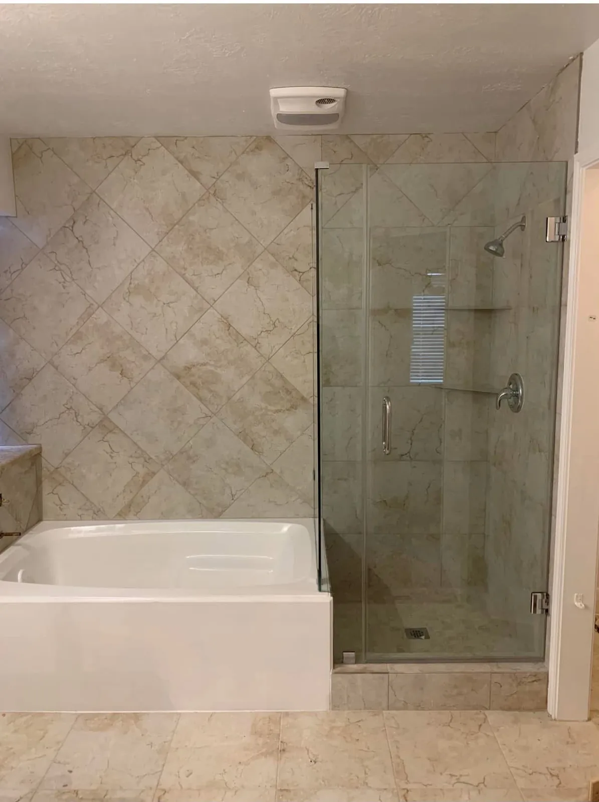 A Houston bathroom updated with marble look tile around the tub and a glass shower after the remodel