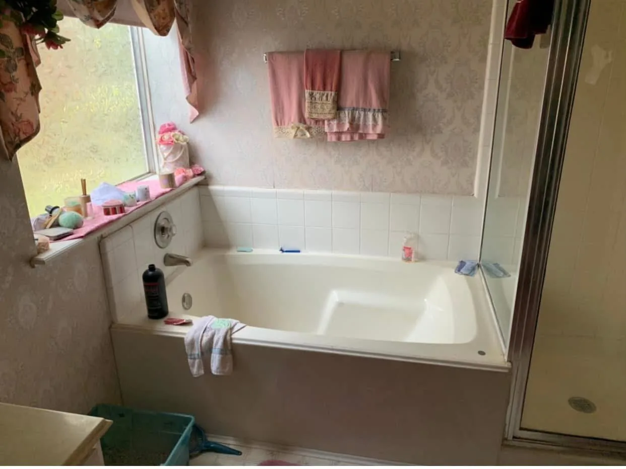 A Houston bathroom updated with marble look tile around the tub and a glass shower before the remodel