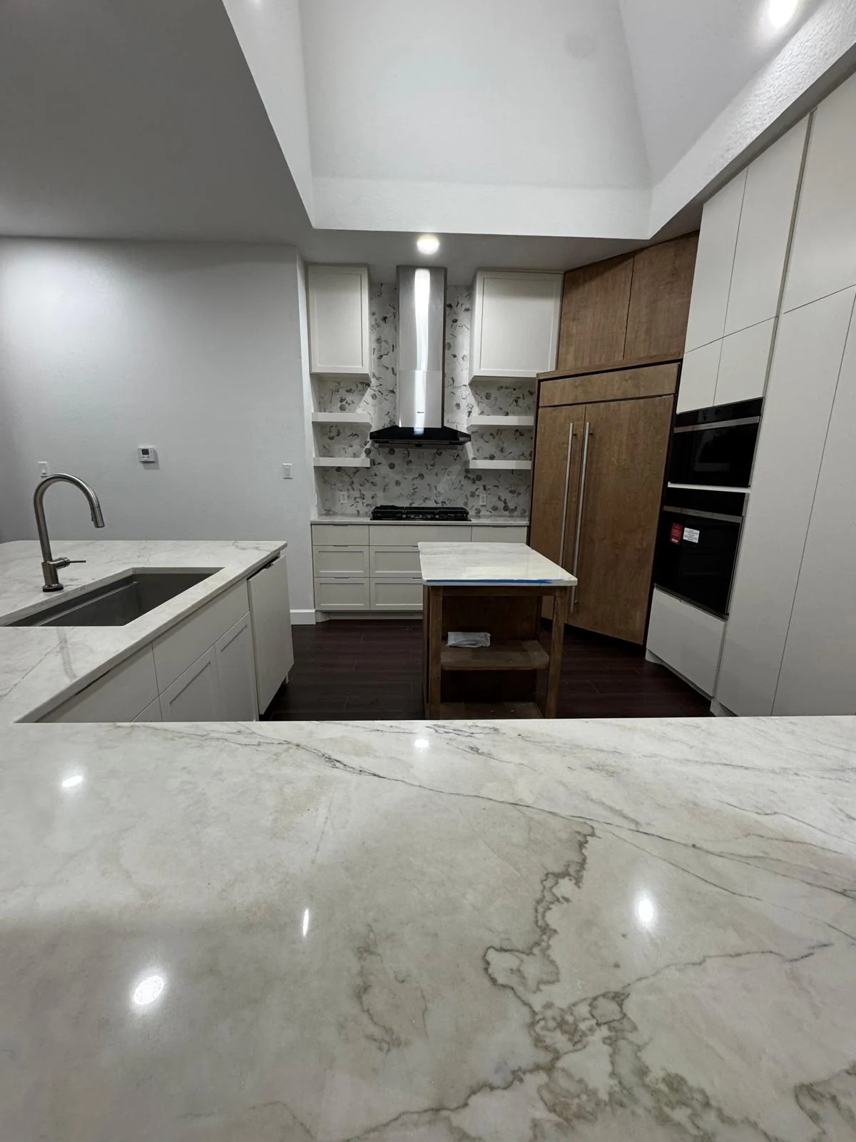 Kitchen by LL General Contractor with a marble waterfall counter and walnut cabinetry
